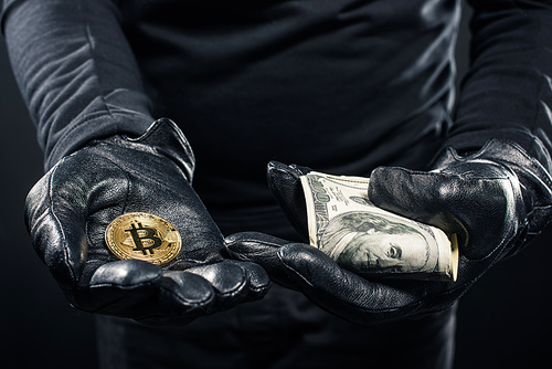 Close-up view of dollars and bitcoin in hands of thief