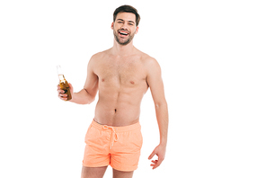 handsome young shirtless man in shorts holding bottle of summer drink and smiling at camera isolated on white