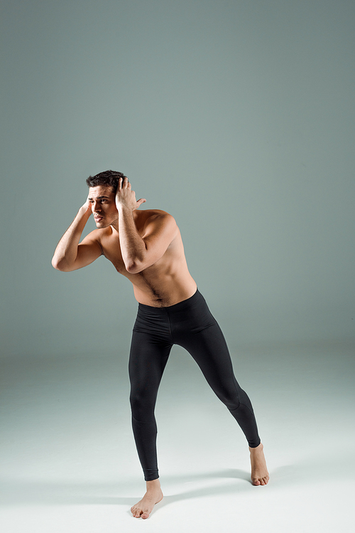 handsome dancer in black leggings dancing contemporary on dark background