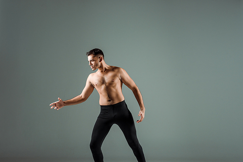 handsome dancer in black leggings dancing contemporary isolated on grey