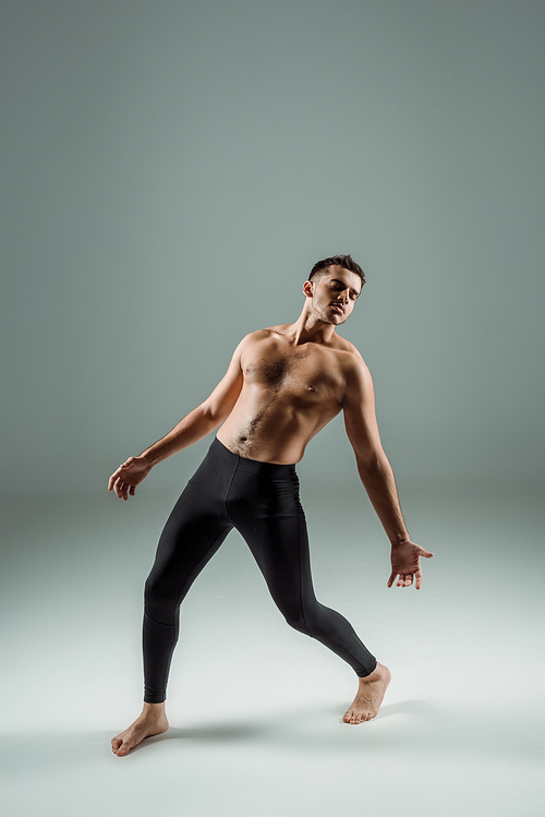 handsome dancer with closed eyes in black leggings dancing contemporary on dark background