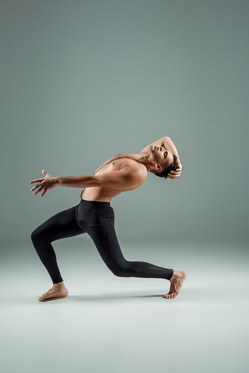 side view of handsome dancer with closed eyes in black leggings dancing contemporary on dark background