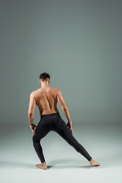 back view of dancer in black leggings dancing contemporary on dark background