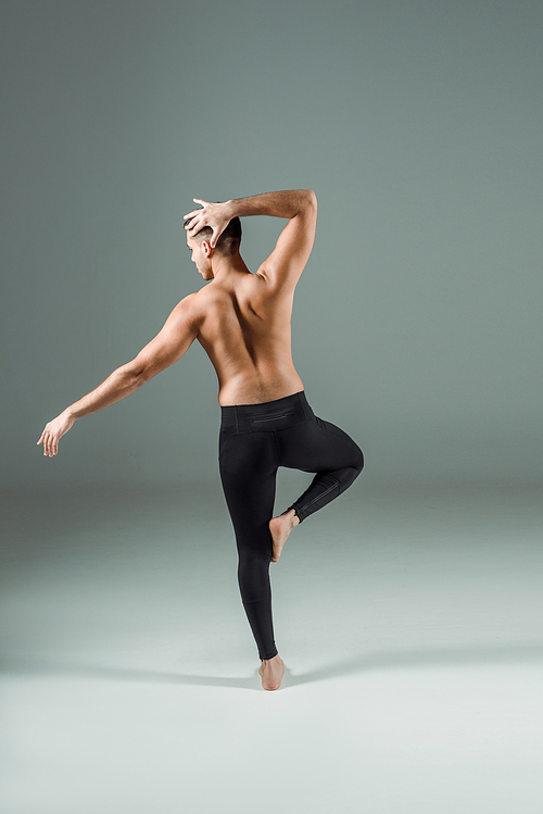 back view of dancer in black leggings dancing contemporary on dark background