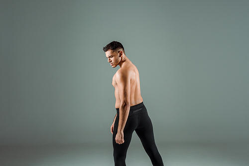 handsome dancer in black leggings dancing contemporary on grey background