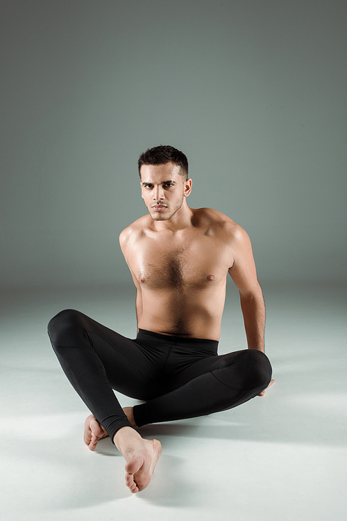 handsome dancer in black leggings dancing contemporary on dark background