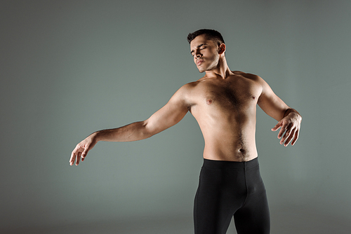 handsome dancer with closed eyes in black leggings dancing contemporary isolated on grey