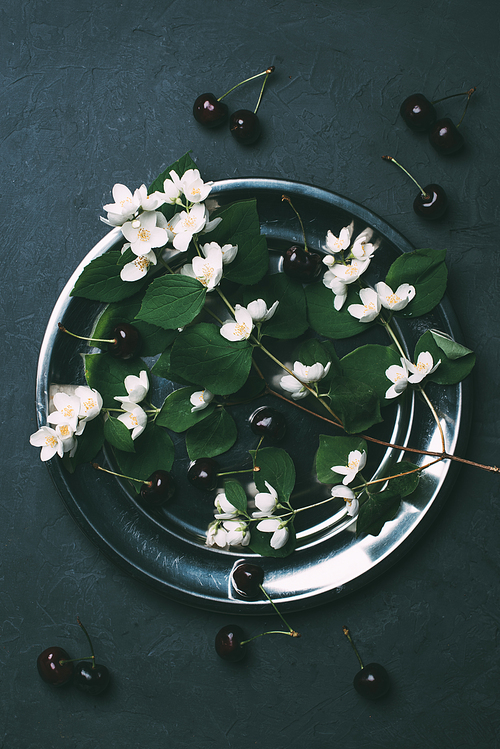 top view of beautiful white jasmine flowers and ripe sweet cherries on black