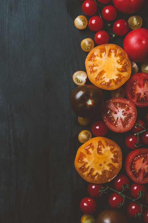 top view of different ripe tomatoes on wooden background with copy space