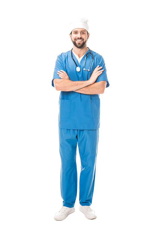 full length view of bearded surgeon standing with crossed arms and smiling at camera isolated on white