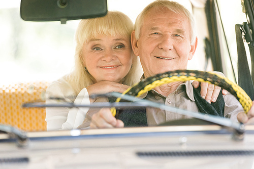 senior woman embracing driving man in retro car