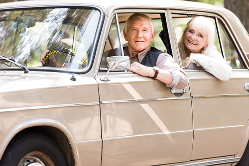 side view of attractive senior couple in beige car