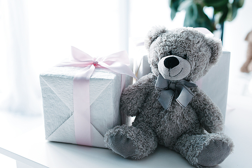 selective focus of teddy bear with gift boxes on table