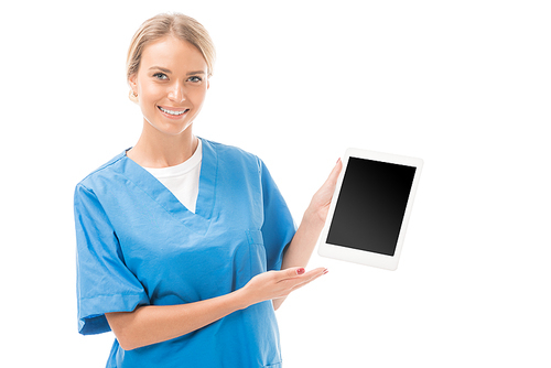 smiling young nurse pointing at tablet with blank screen isolated on white