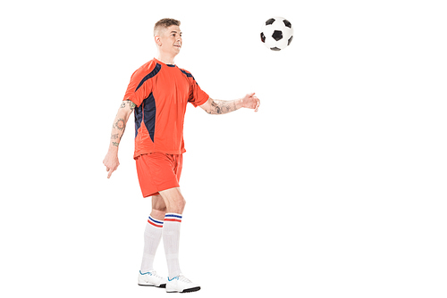 full length view of smiling young soccer player kicking ball isolated on white