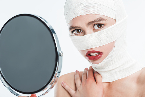 close up of woman with bandages over head holding mirror and  isolated on white