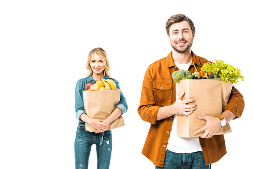 handsome smiling man holding shopping bag with products while his girlfriend standing behind isolated on white