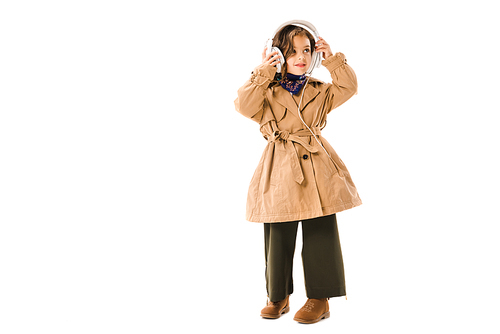 beautiful little child in trench coat with headphones isolated on white