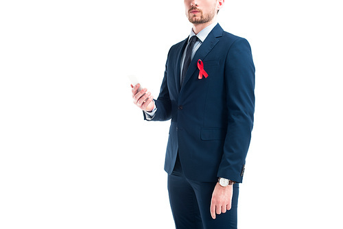 cropped image of businessman with red ribbon on suit holding smartphone isolated on white, world aids day concept
