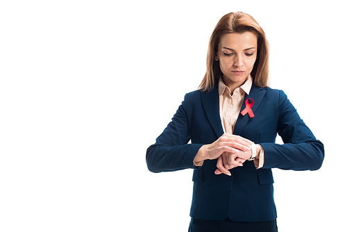 attractive businesswoman with red ribbon on suit checking time isolated on white, world aids day concept