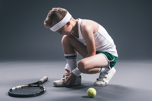 preteen boy in sportswear with tennis racket and ball on dark background