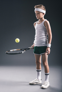 preteen boy in sportswear with tennis racket and ball on dark background