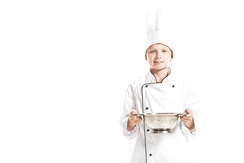 portrait of smiling boy in white chef uniform with colander isolated on white