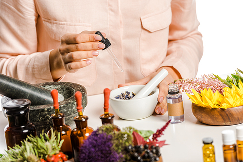 cropped image of woman adding essential oil to natural medicines isolated on white