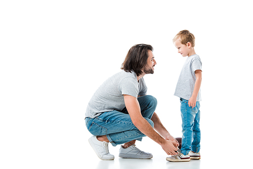 Caring father helping his son to tie shoelace isolated on white