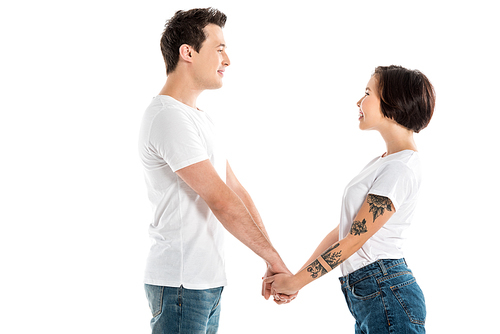 smiling couple holding hands and looking at each other isolated on white