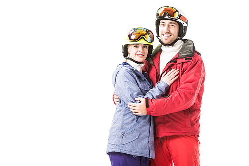 Couple in ski suits, goggles and helmets hugging, smiling and  isolated on white