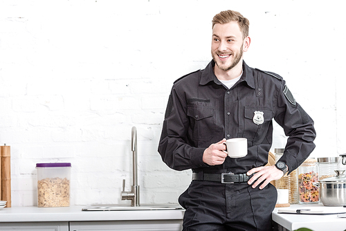 Handsome police officer drinking coffee at kitchen