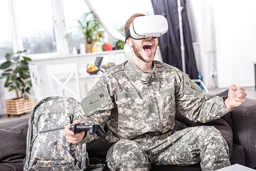 excited soldier in virtual reality headset playing video game on couch