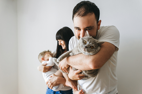 portrait of happy parents holding little toddler boy and grey cat at home