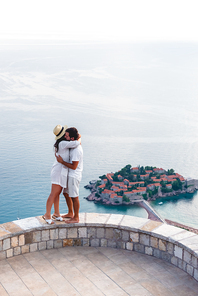 couple hugging on viewpoint near island of Sveti Stefan with hotel resort in Adriatic sea, Budva, Montenegro