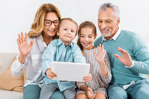 kids and grandparents waving by hands while having video call with digital tablet at home