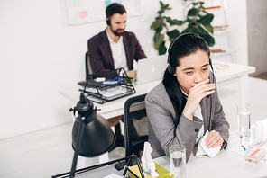 sick call center operator touching nose and holding napkin in office