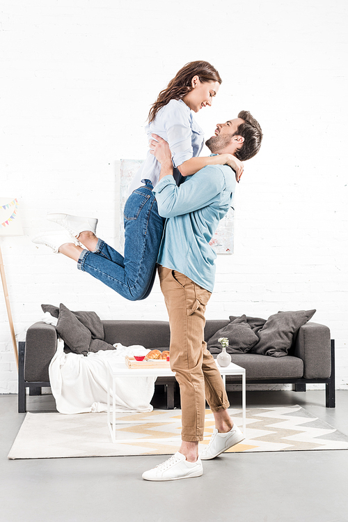 happy man in casual clothes holding woman in living room