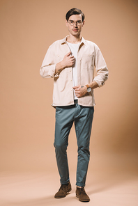 handsome man with watch on hand standing on beige background