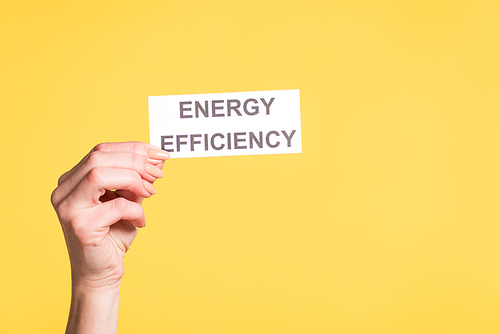 cropped view of female hand holding paper card with lettering isolated on yellow, energy efficiency concept