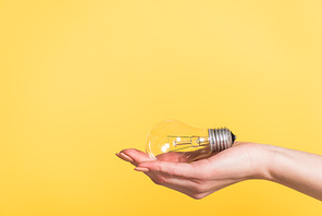 cropped view of woman holding led lamp isolated on yellow, energy efficiency concept