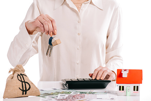 cropped view of businesswoman holding keys and using calculator isolated on white, mortgage concept
