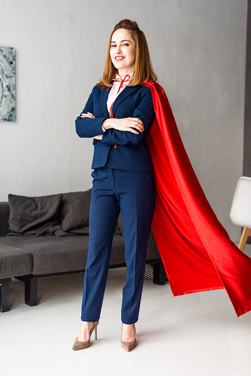 smiling businesswoman with crossed hands in blue suit and red cape 