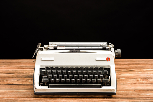 vintage typewriter on wooden table isolated on black