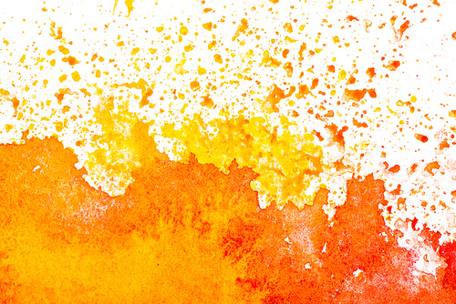 top view of yellow and orange watercolor spills on white background