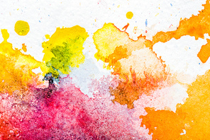 top view of yellow, orange and pink watercolor spills on white paper