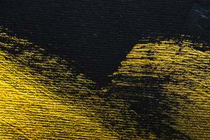 top view of yellow watercolor brushstrokes with copy space on black paper