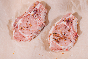 top view of raw fresh steaks with seasoning on paper