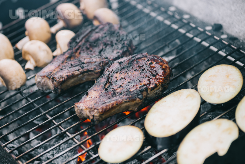유토이미지 | selective focus of juicy tasty steaks grilling on hot coals with mushrooms and sliced eggplant