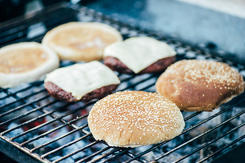 selective focus of delicious fresh burgers ingredients grilling on barbecue grid